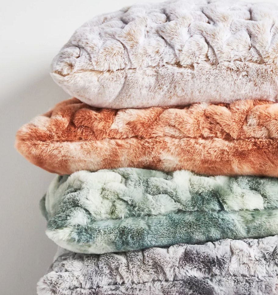 stack of fuzzy throw pillows in various colors