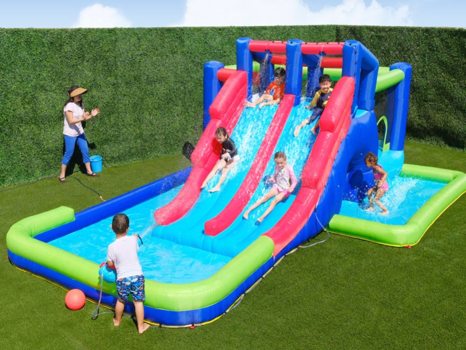 lots of kids playing on a large inflatable water slide