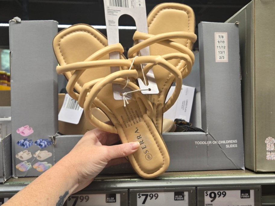 hand holding tan strappy sandals 