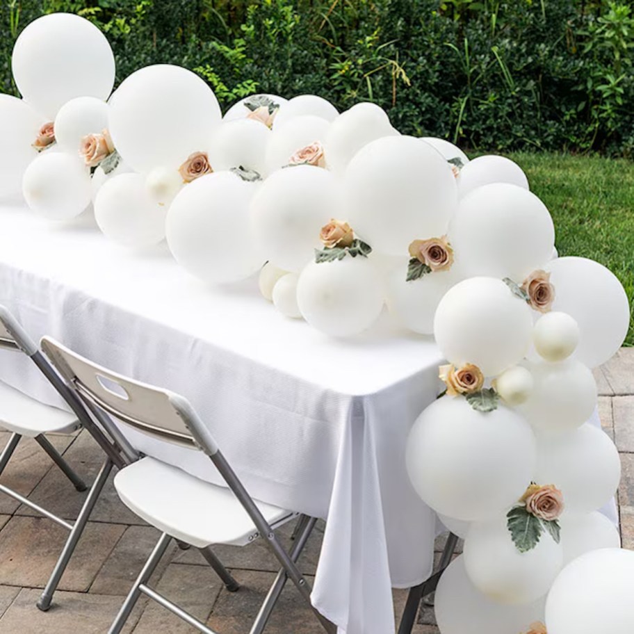 white balloon garland with pink flowers on table