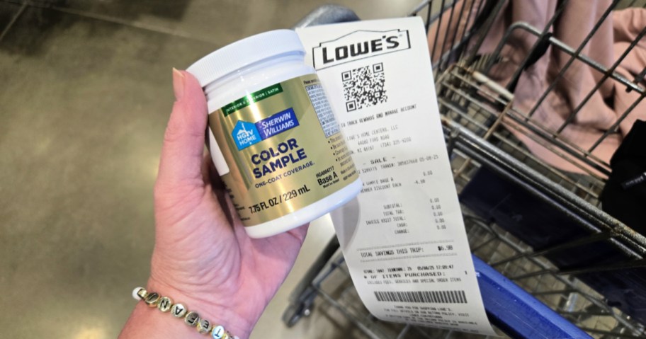 hand holding a jar of paint and a lowe's receipt
