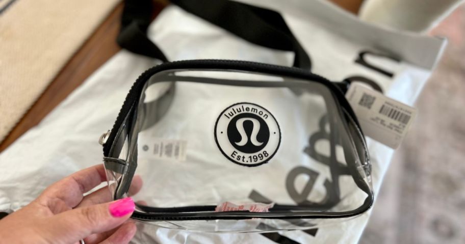 a hand holding a lululemon clear belt bag on counter