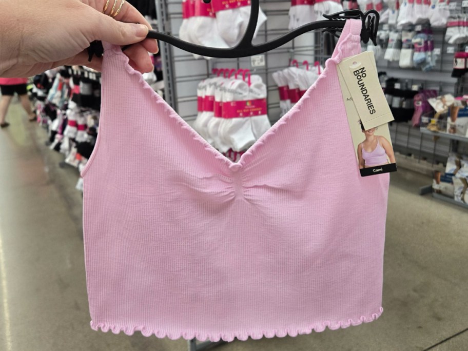 No Boundaries Ruffle Cami in pink being held in a Walmart aisle