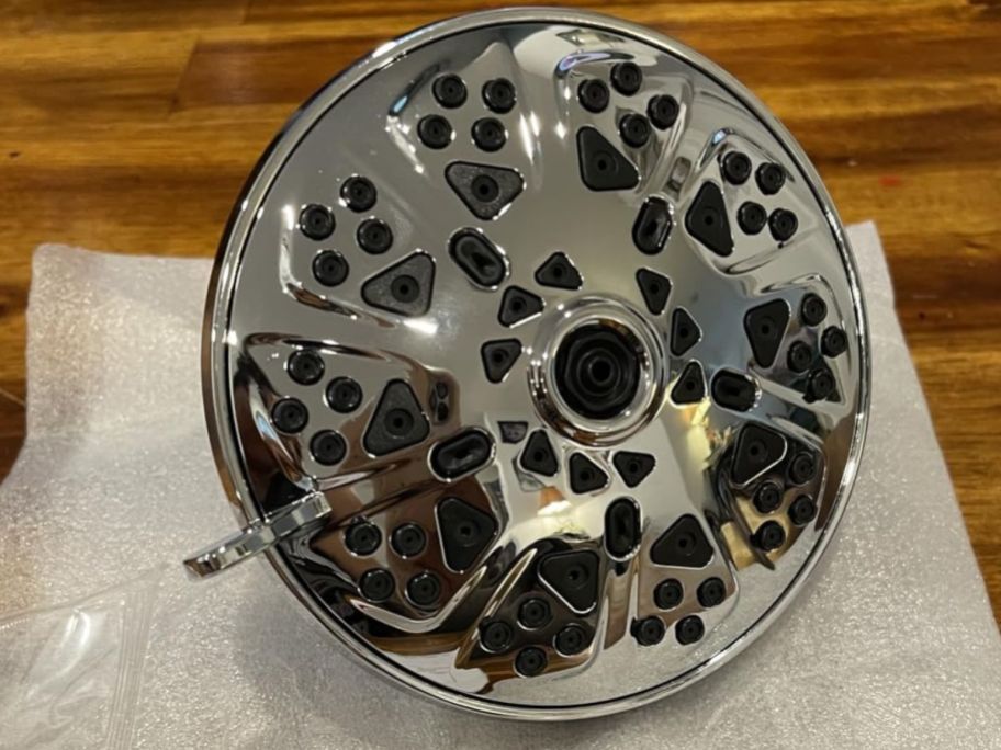 silver showerhead displayed on a paper that has been placed on the floor